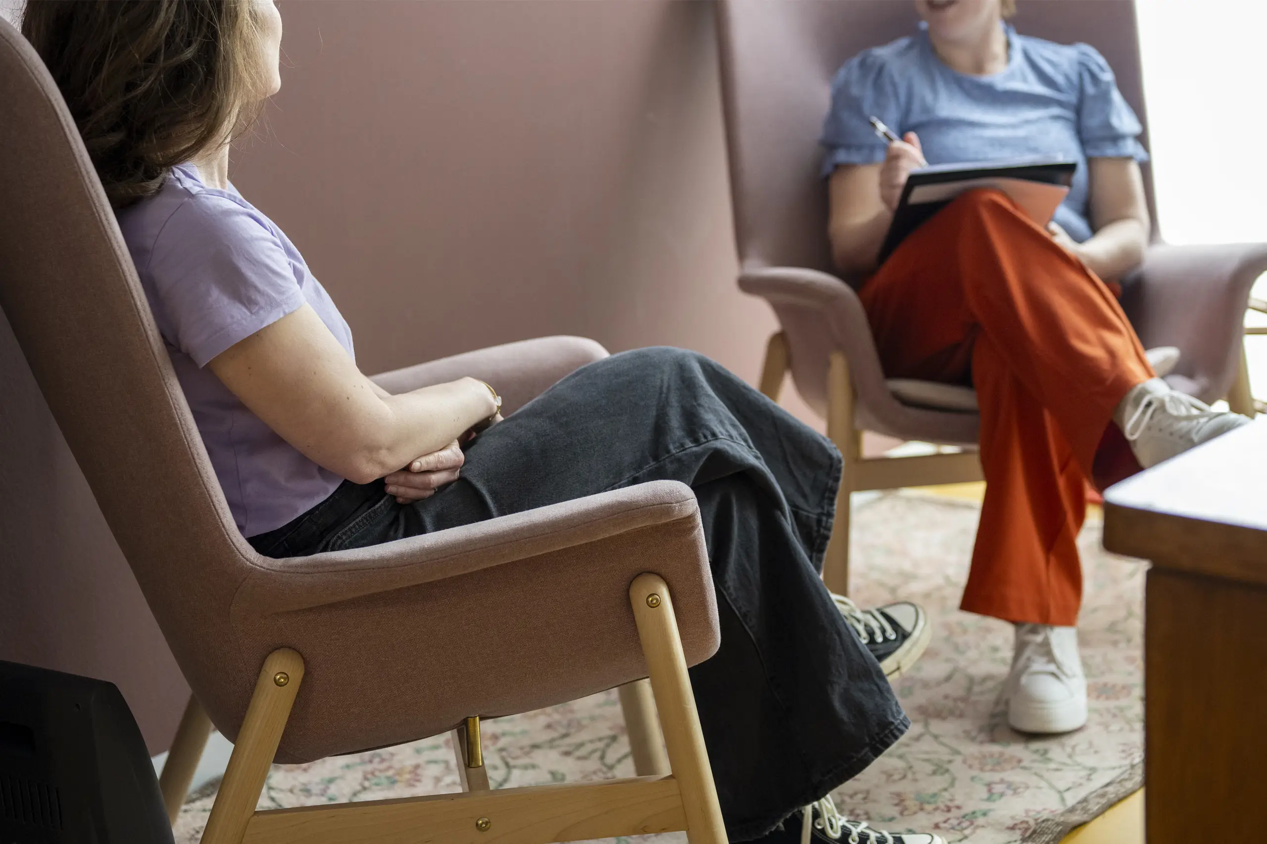 Dos personas conversando sentadas en sillones en un entorno de consulta