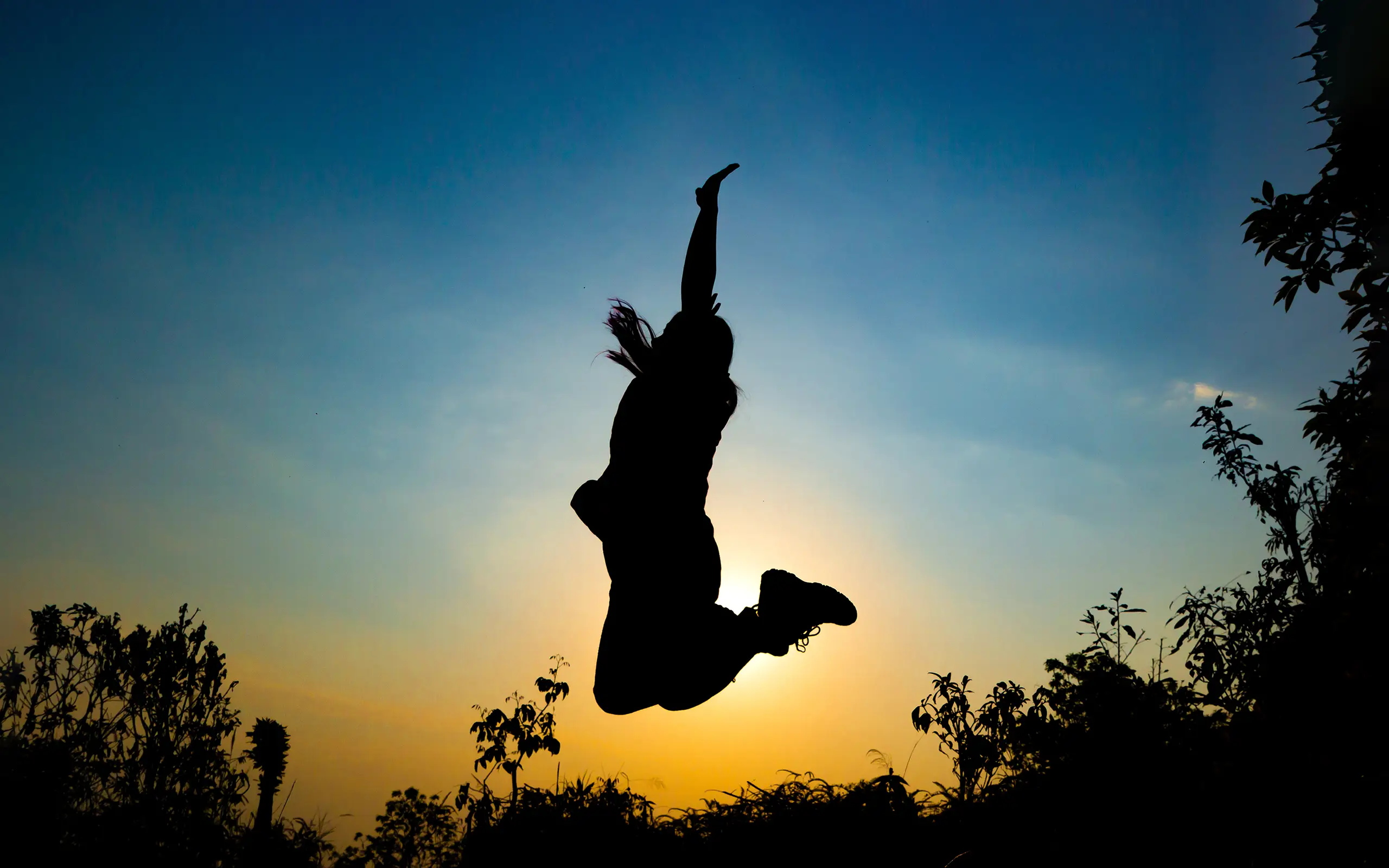 Silueta de una persona saltando al atardecer con el cielo de fondo